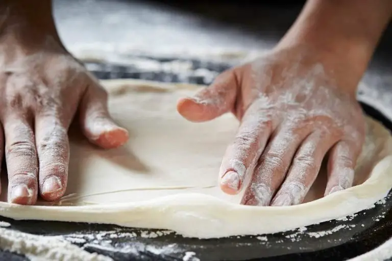 two hands making pizza dough