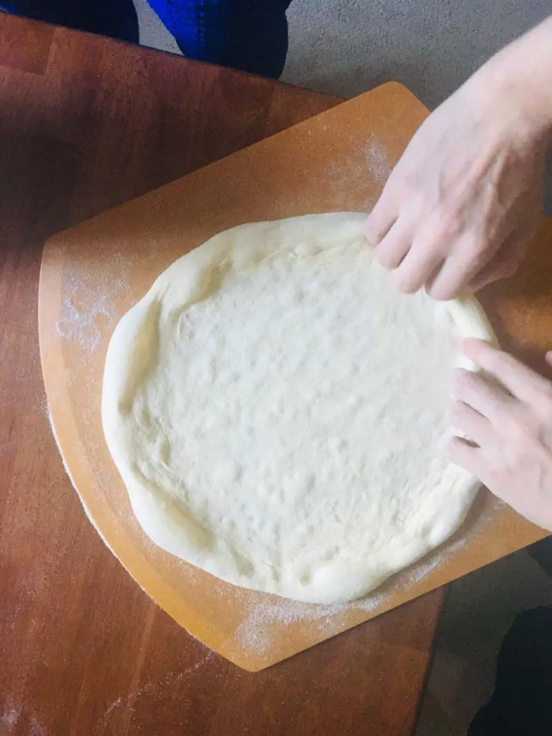 stretching a pizza dough on a pizza peel