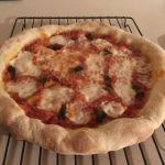 A homemade pizza resting on a cooling rack to avoid a soggy middle crust.