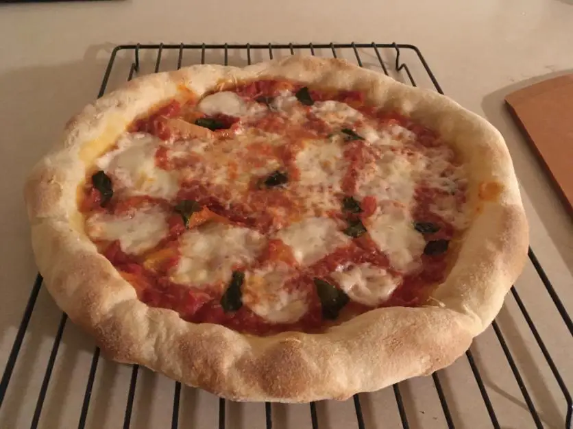 A homemade pizza resting on a cooling rack to avoid a soggy middle crust.