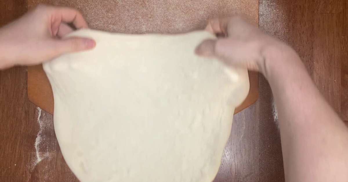 stretching homemade pizza dough over a pizza peel