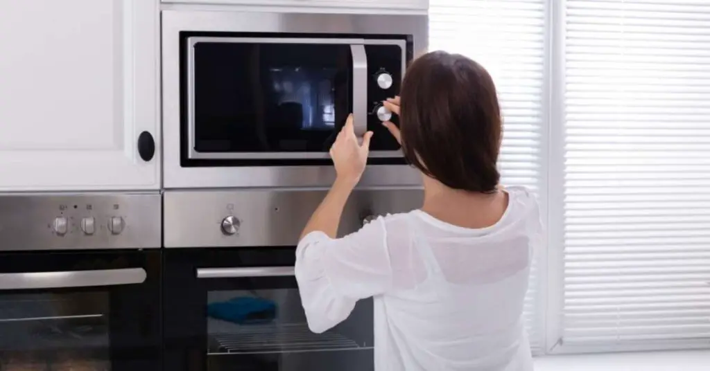 How to Cook Pizza In A Microwave: Fresh or Frozen, With Or Without Convection 3 woman using microwave How to Cook Pizza In A Microwave: Fresh or Frozen, With Or Without Convection