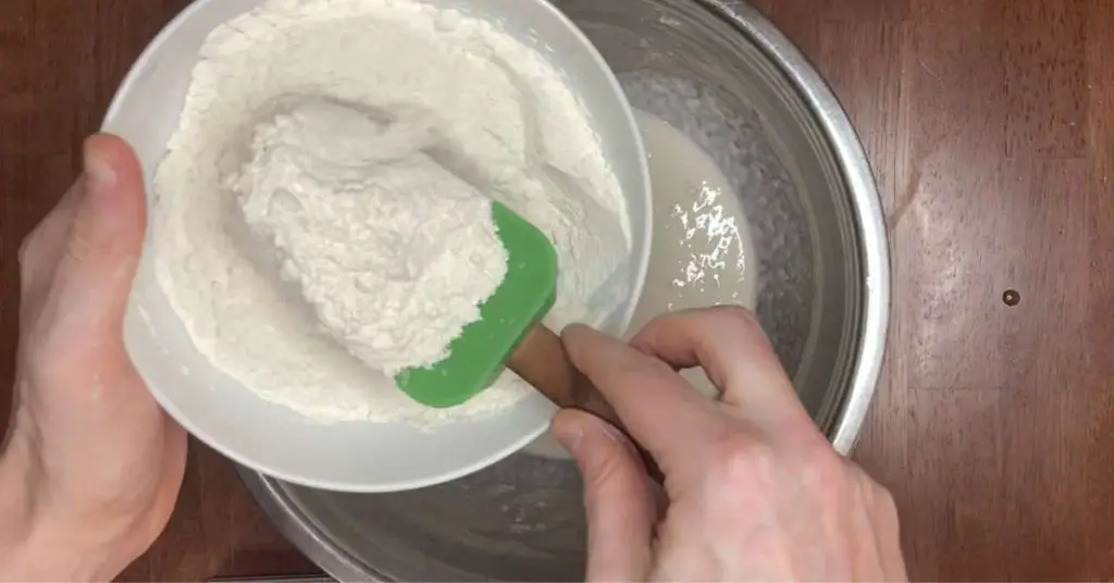scooping flour into a mixing bowl to make pizza dough