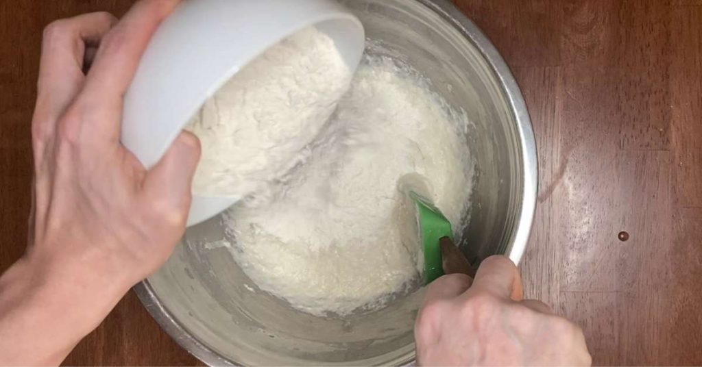 pouring flour into a mixing bowl to make pizza dough