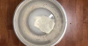 dissolving poolish in water in a large mixing bowl