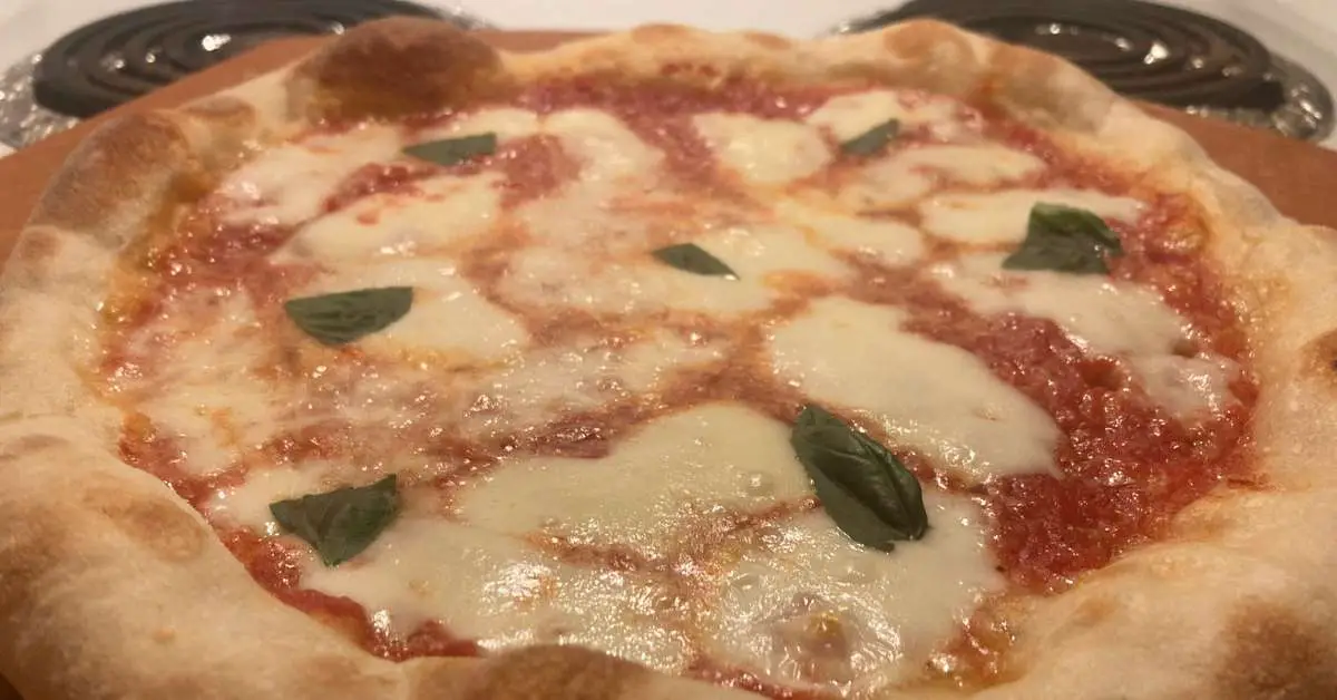 A homemade Neapolitan style pizza sitting uncut on top of the oven.