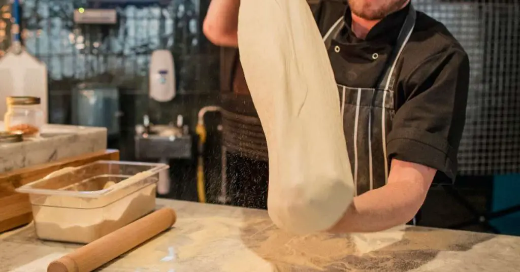 stretching pizza dough with knuckles Why Is My Pizza Dough Not Stretching? How to Fix Elastic Pizza Dough That Springs Back When You Stretch It