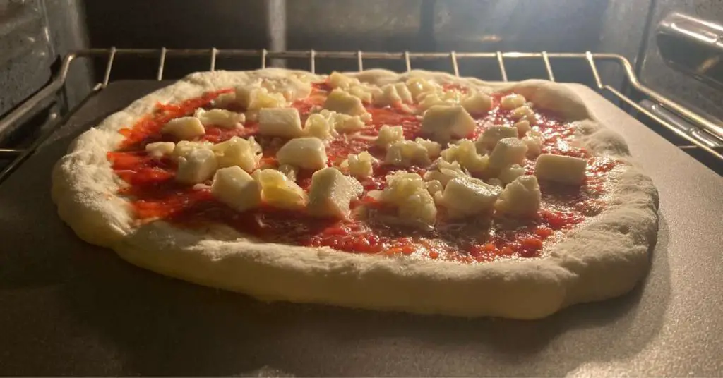 A homemade pizza baking on a pizza steel in a hot oven.