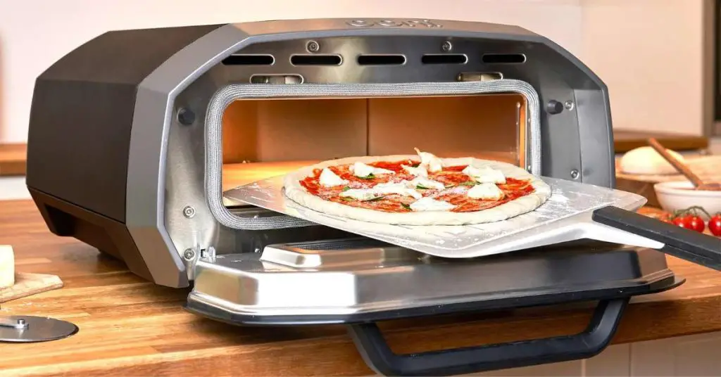 a fresh pizza sliding into the Ooni Volt 12 indoor pizza oven