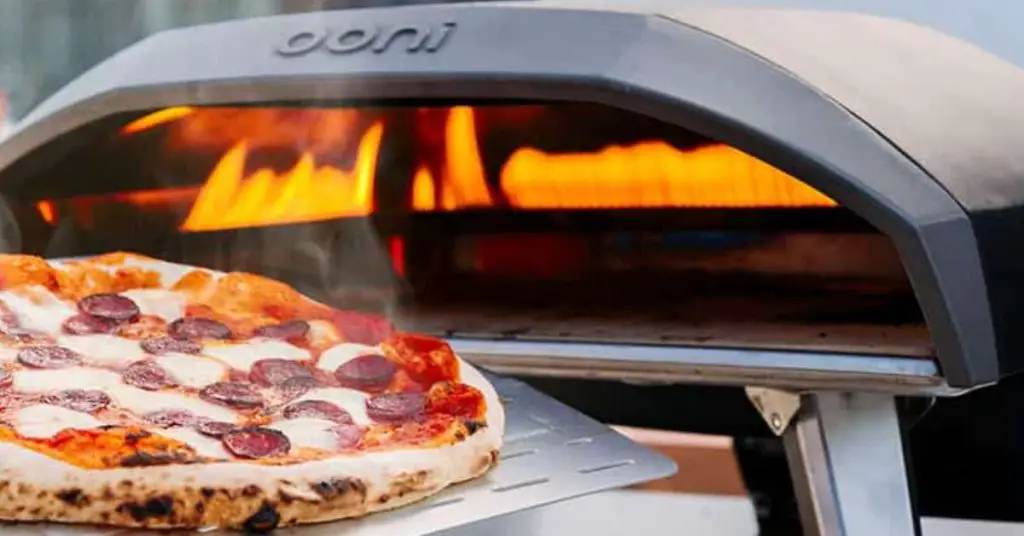 a pepperoni pizza coming out of a gas Ooni Koda 16 outdoor pizza oven