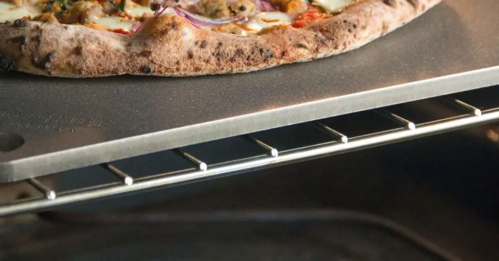 A nerdchef pizza steel stone sitting on an oven rack with a pizza cooking on it.