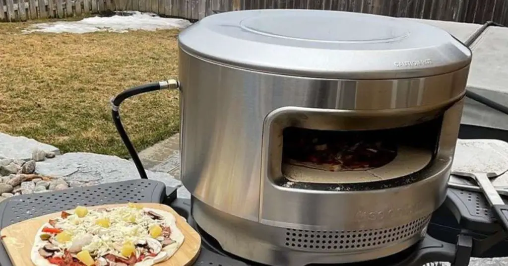 solo pi outdoor pizza oven sitting on its stand with an uncooked pizza next to it