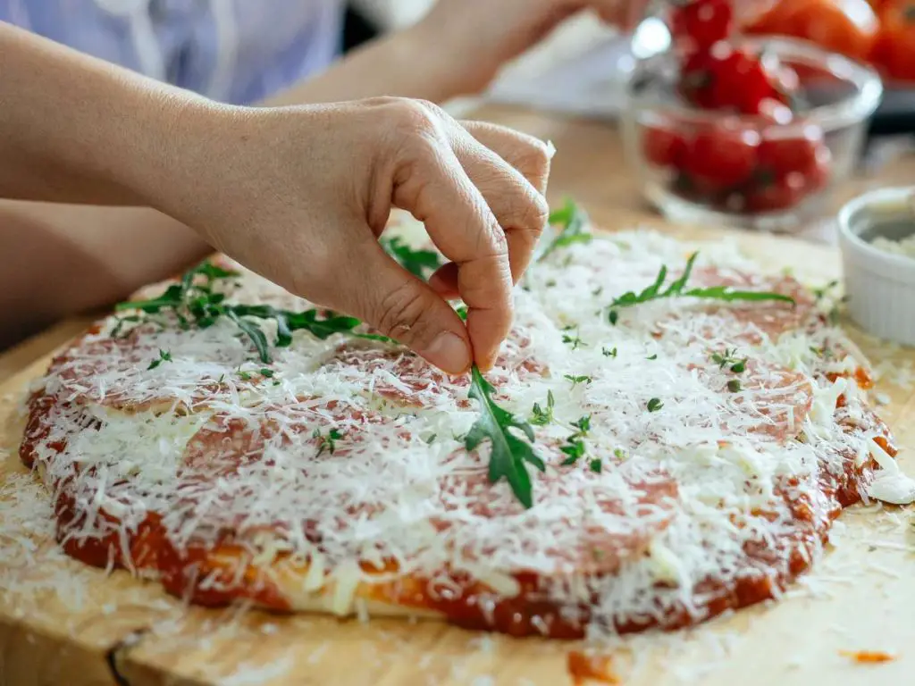 Putting the finishing touches on a homemade pizza before cooking it.