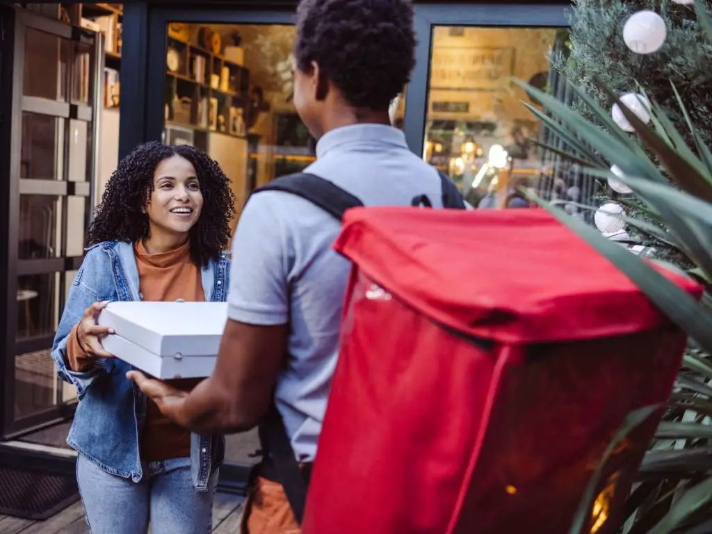 A young woman meeting a pizza delivery man.