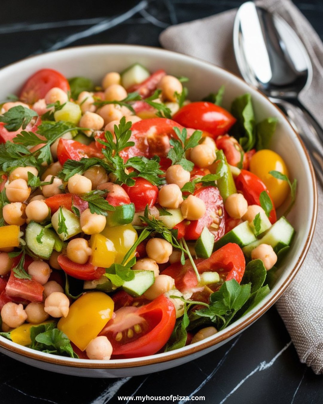 Italian Chickpea Salad Recipe for a Healthy and Delicious Side Dish 1 A vibrant Italian chickpea salad with colorful vegetables and fresh herbs served in a white ceramic bowl on a black quartz marble countertop.
