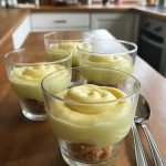 Delicious individual Limoncello basil cloud cups with a creamy yellow topping and a crunchy cookie base, displayed on a wooden kitchen countertop.