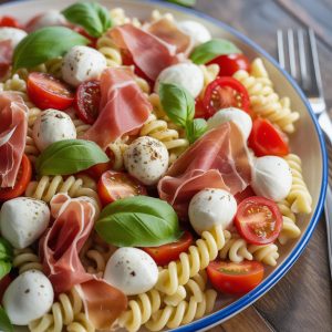 Summer Italian Pasta Salad with Mozzarella and Prosciutto Recipe 7 A beautifully arranged Classic Italian Pasta Salad featuring tri-color rotini pasta, fresh mozzarella balls, cherry tomatoes, and thinly sliced prosciutto, garnished with vibrant basil leaves, perfect for summer picnics or gatherings.