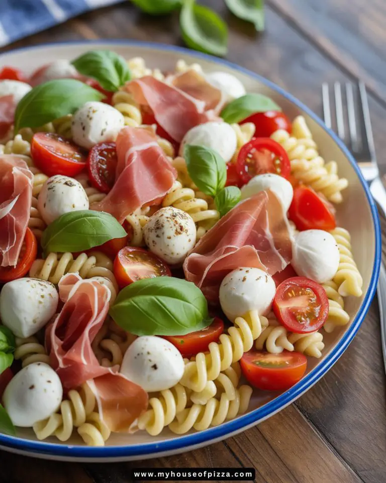 A beautifully arranged Classic Italian Pasta Salad featuring tri-color rotini pasta, fresh mozzarella balls, cherry tomatoes, and thinly sliced prosciutto, garnished with vibrant basil leaves, perfect for summer picnics or gatherings.