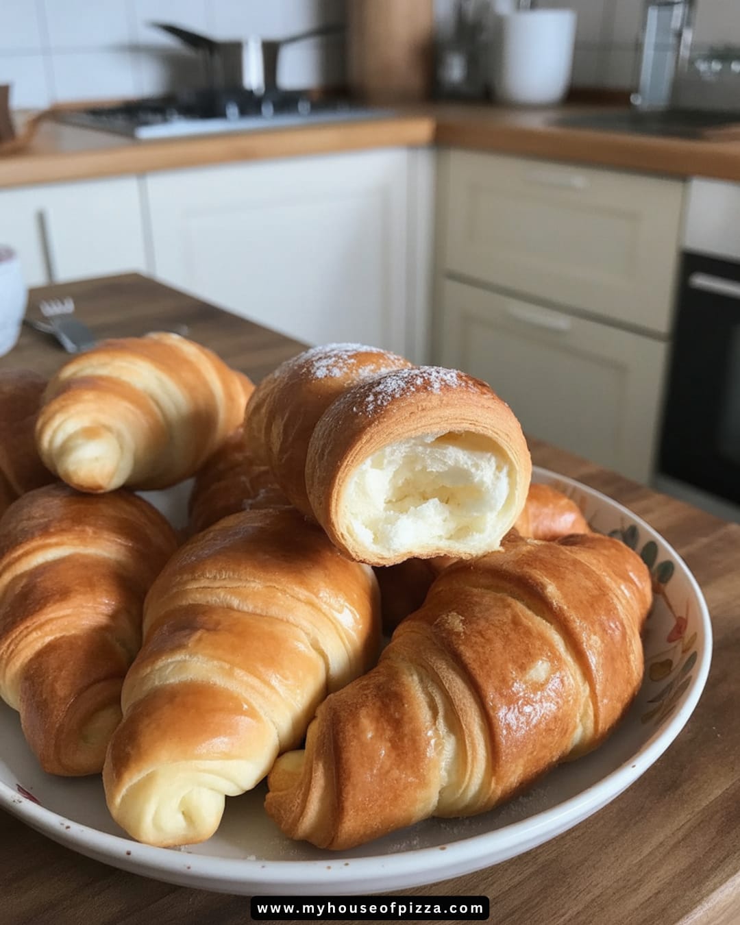 Italian Cornetti Recipe: How to Make a Classic Italian Pastry 1 Freshly baked, golden-brown croissants arranged on a plate, showcasing their flaky texture and a partially visible creamy filling, set against a cozy kitchen backdrop. Perfect for a delightful breakfast or snack.